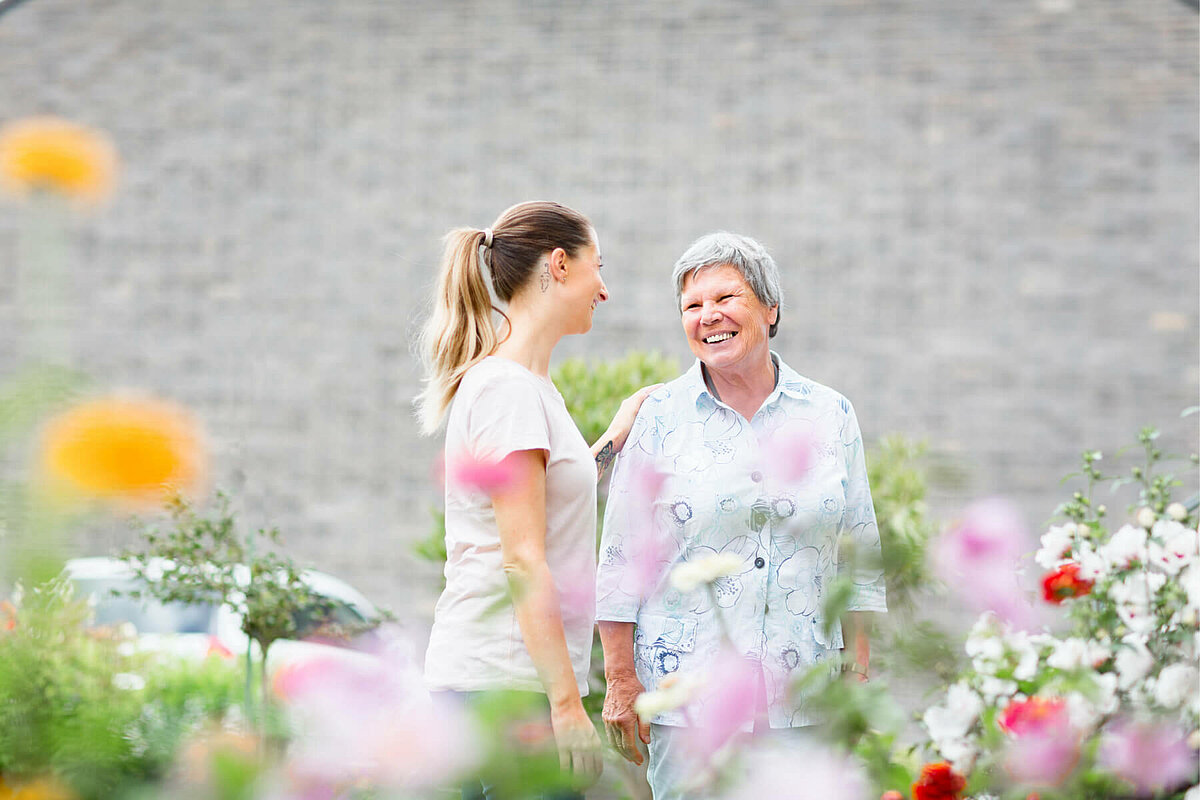 Praktikantin mit Seniorin im Garten eines Seniorenheims