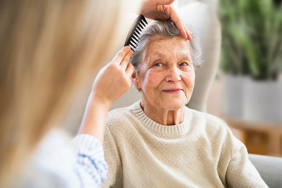 Seniorin wird im Pflegeheim gekämmt